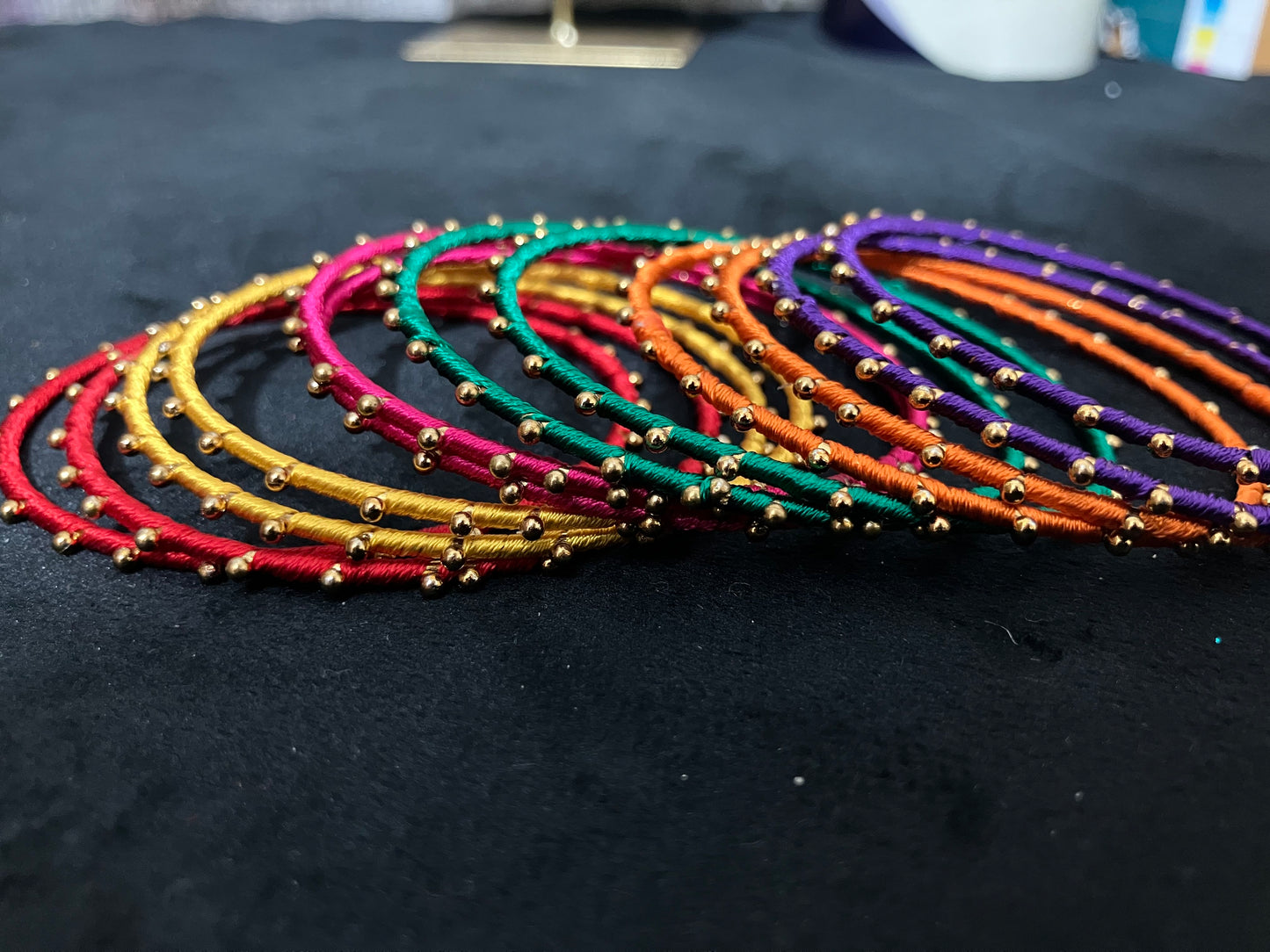 Silk Thread-wrapped metal bangles featuring gold-toned balls