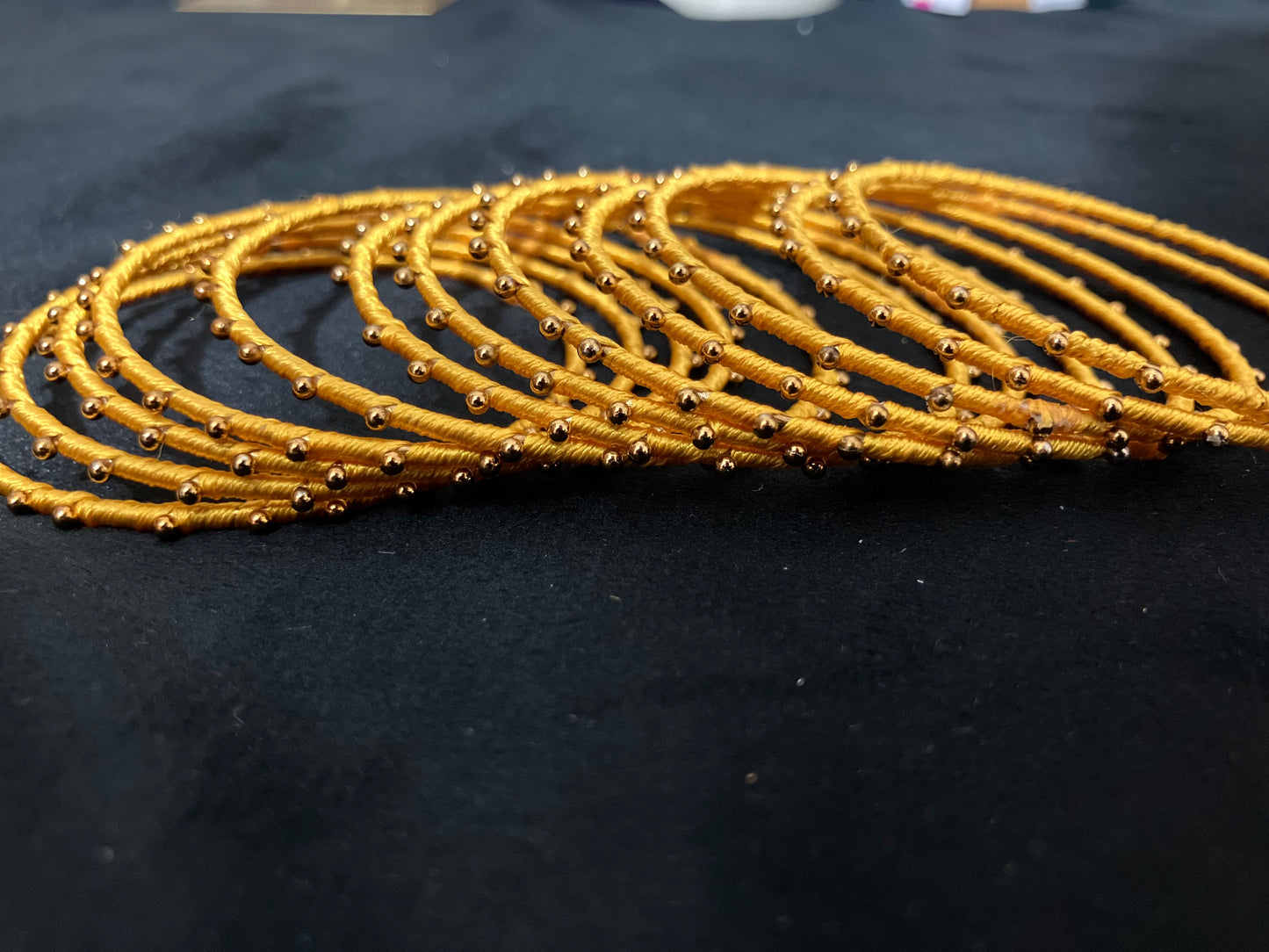 Silk Thread-wrapped metal bangles featuring gold-toned balls